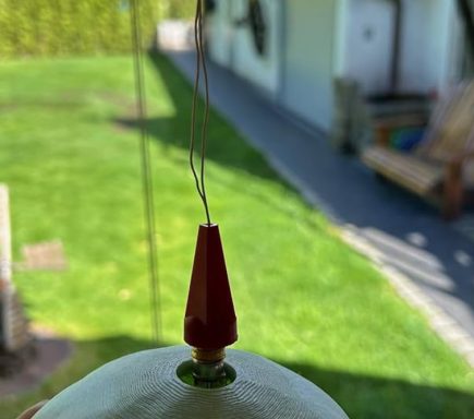 Nahaufnahme eines roten, konischen Gegenstands auf einem weißen Untergrund, im Freien.