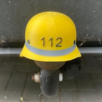 Gelbes Sicherheitshelmkäppchen mit der Nummer 112 und grauem Streifen.