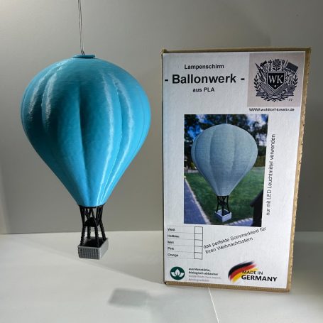 Blaue Luftballonmodell mit schwarzem Korb neben Verpackung.