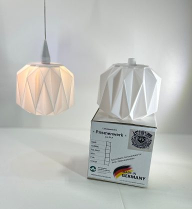 Hängelampe in geometrischer Form über einem weißen Karton.