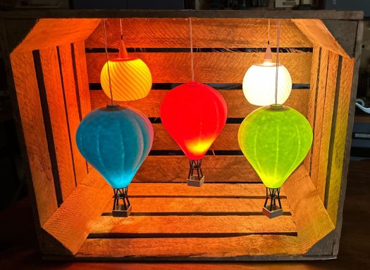 Bunte, beleuchtete Luftballons in einer Holzbox.