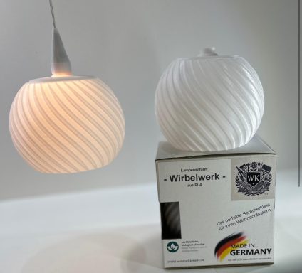 Hängelampe in weißer, gewellter Form über einer Verpackung.