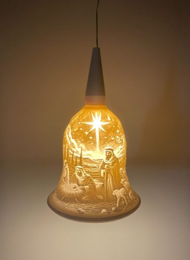 Eine beleuchtete Glocke mit einem Weihnachtsmotiv darunter, strahlend und festlich.