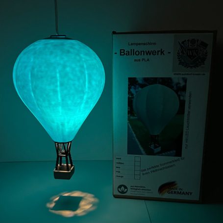 Leuchtende, blaue Heißluftballonlampe neben Verpackung.