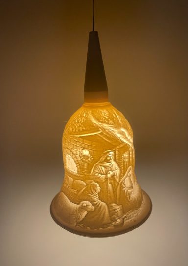 Glaslampe mit filigranen Reliefs von Figuren und Szenen, warm leuchtend.