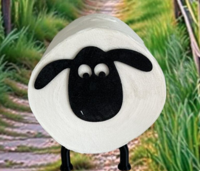 Schaf mit schwarzem Gesicht und großen Augen auf einem grünen Weg.