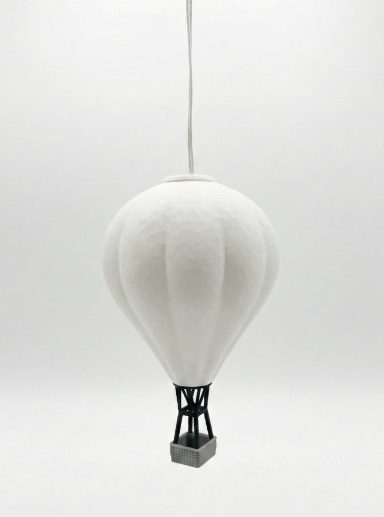 Weißer Heißluftballon mit schwarzem Korb, schwebend vor einem hellen Hintergrund.