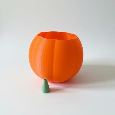 Orangene Kürbisform mit grüner Kegelform daneben auf hellem Hintergrund.