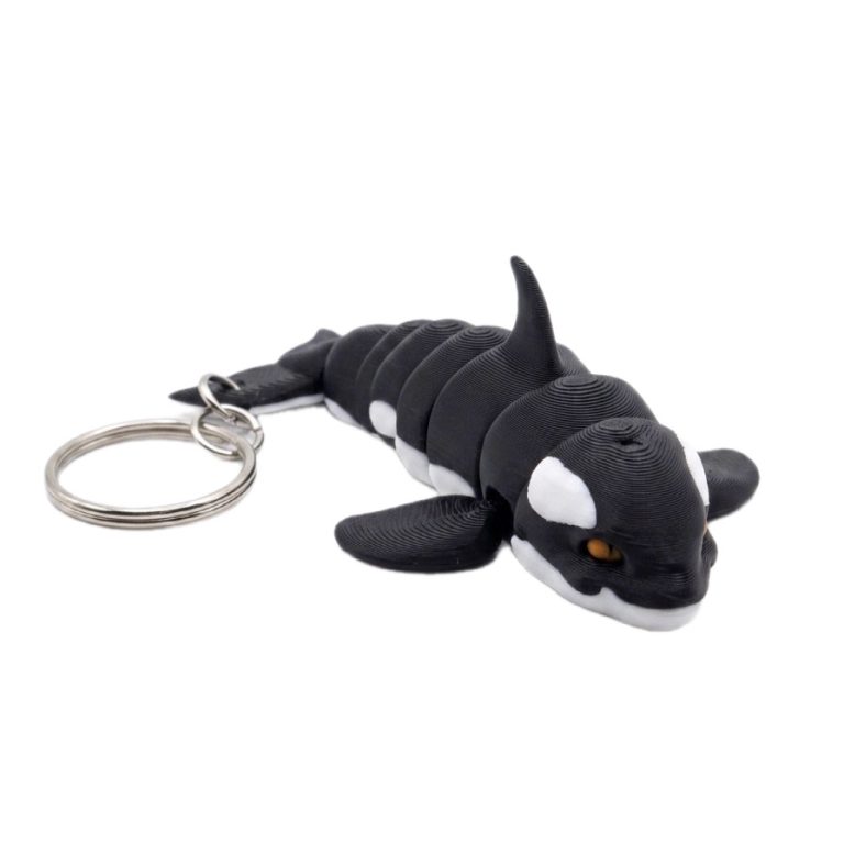 Schlüsselanhänger in Form eines Orcas mit beweglichem Körper und orangefarbenen Augen.