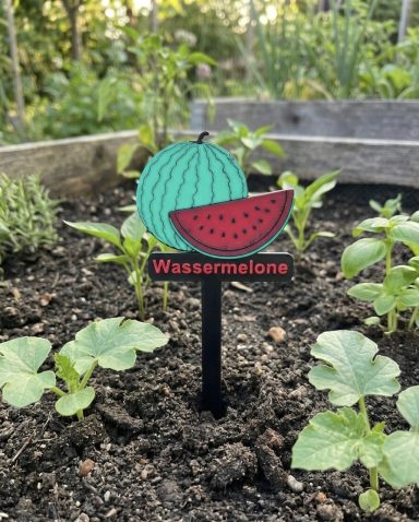 Bodenstecker mit einer Wassermelone und dem Schriftzug "Wassermelone" im Garten.