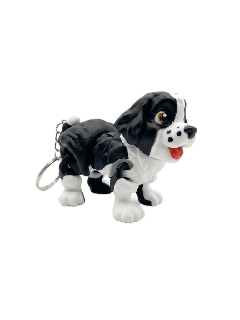 Schwarzer und weißer Plüschhund mit Schlüsselanhänger, freundlich lächelnd.